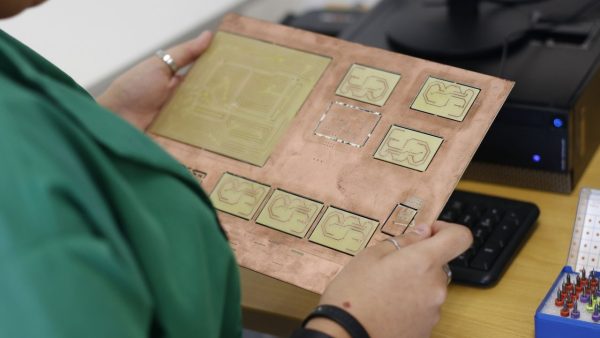 Técnico examina uma placa de circuito em um laboratório de eletrônica.