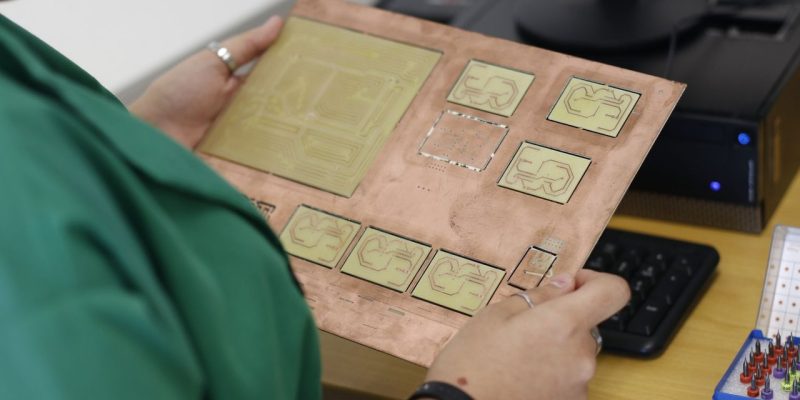 Técnico examina uma placa de circuito em um laboratório de eletrônica.
