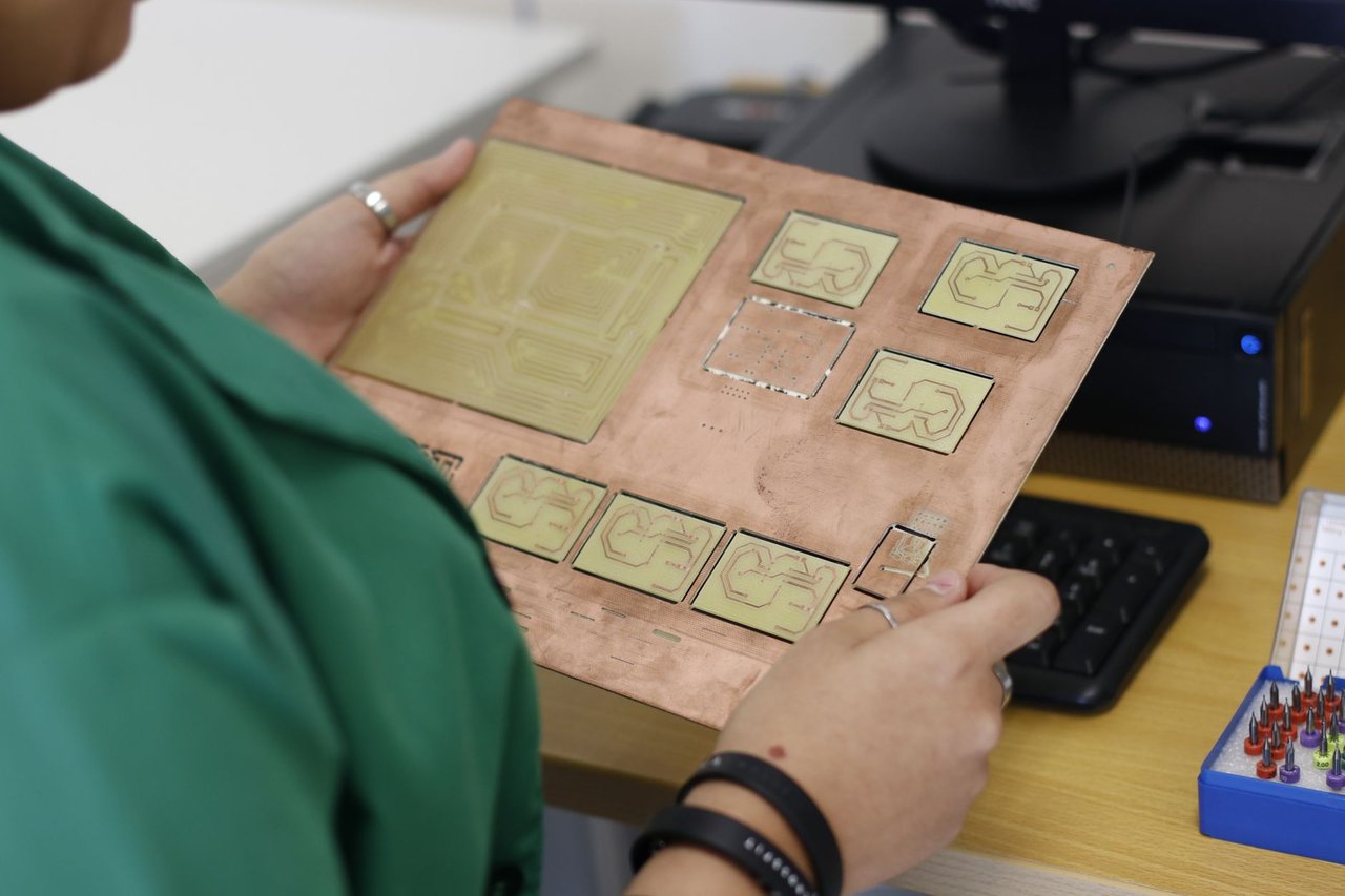 Técnico examina uma placa de circuito em um laboratório de eletrônica.