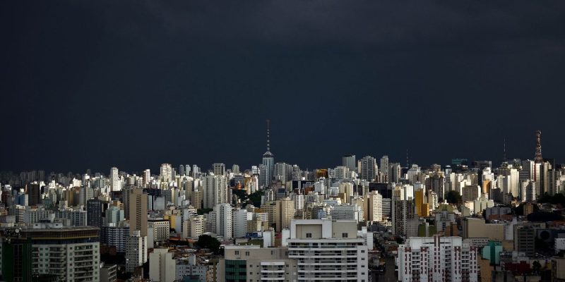 Vista do horizonte urbano de São Paulo sob nuvens escuras de tempestade.