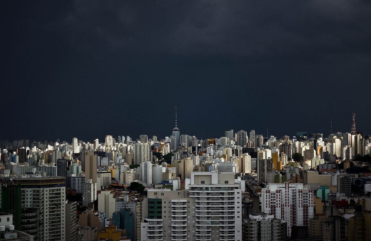 Vista do horizonte urbano de São Paulo sob nuvens escuras de tempestade.