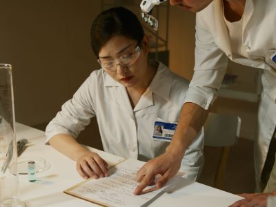 Pesquisadores de jaleco analisam anotações durante um estudo científico em laboratório.