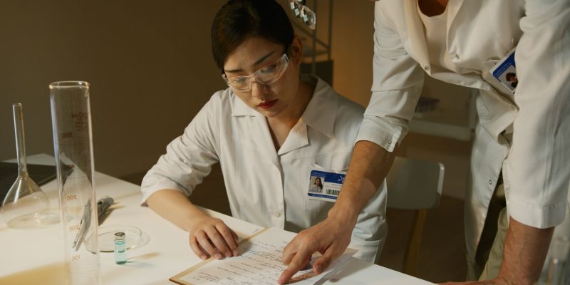Pesquisadores de jaleco analisam anotações durante um estudo científico em laboratório.