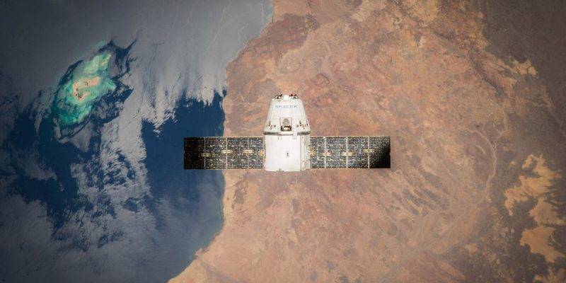 Satélite em órbita sobre a Terra, com o oceano e parte do planeta visíveis ao fundo